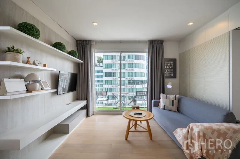 公寓 出租在Watthana, Bangkok - 沙发休闲区连接阳台，落地窗外是城市天际线。