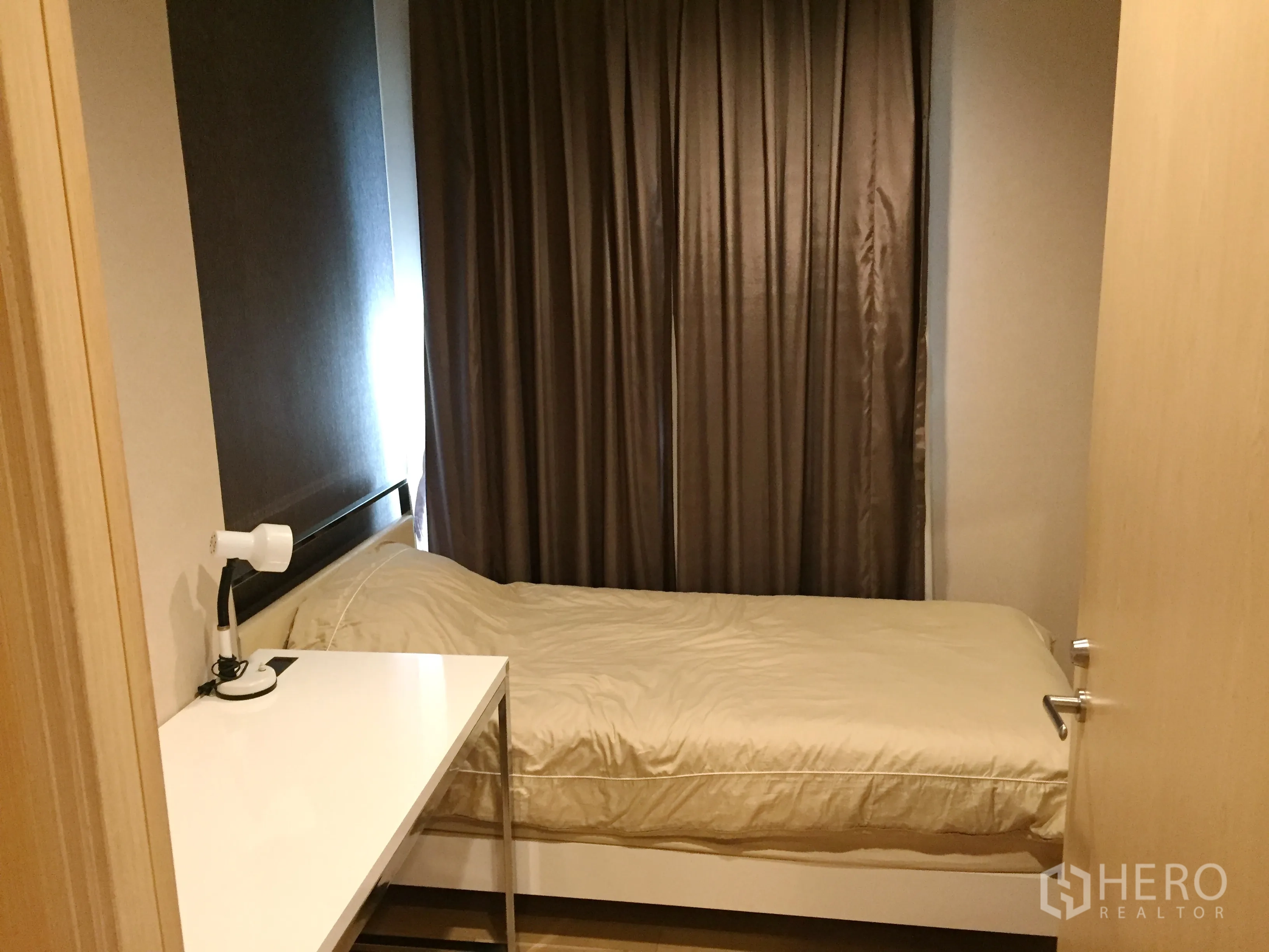Condominium for rent in Khlong Toei, Bangkok - Second bedroom with single bed, study desk and blackout curtains for privacy.
