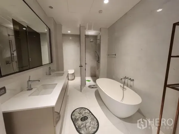 Condominium for sale - Luxurious bathroom with freestanding bathtub, double vanity, walk-in shower, and light marble finishes.
