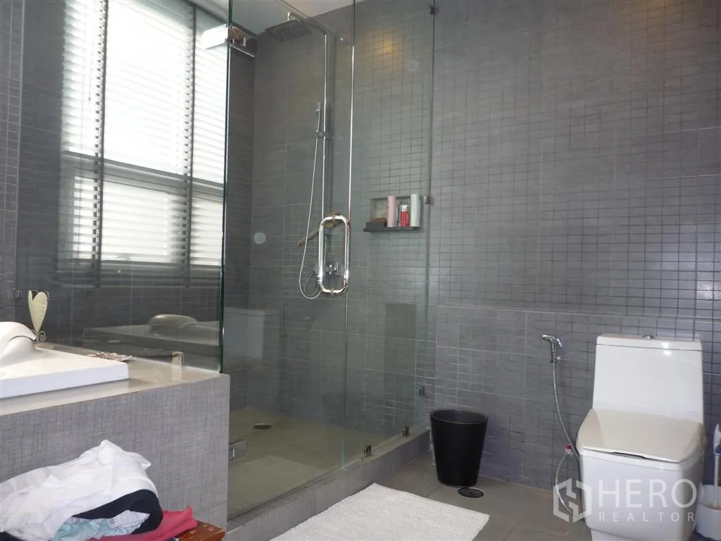 Detached House for rent in Khan Na Yao, Bangkok - Contemporary bathroom with glass-enclosed rain shower, vanity and toilet.