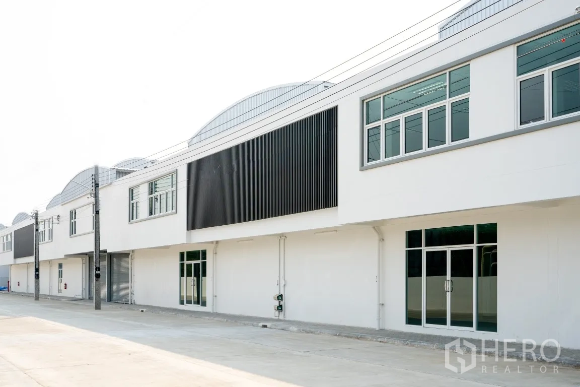 Factory for rent in Khlong Luang, Pathum Thani - Modern factory exterior with large windows, black cladding, and a wide driveway.