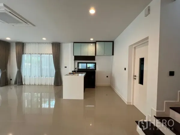 Detached House for rent in Bang Kapi, Bangkok - Living area with pantry and white island beside the staircase and full-height curtains.