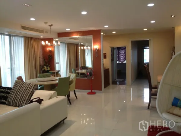 Condominium for rent in Bang Rak, Bangkok - Bright open-plan living and dining area in a Silom condo with sofa, round table, chandelier and floor-to-ceiling curtains.