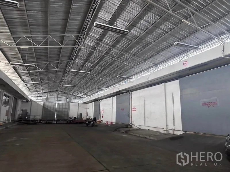 Warehouse for rent in Mueang Samut Prakan, Samut Prakan - Large canopy roof over loading docks with sliding steel doors and industrial lighting.