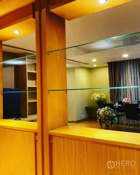 Condominium for rent in Watthana, Bangkok - Close-up of wooden built‑in shelves with glass display panels and spotlights.