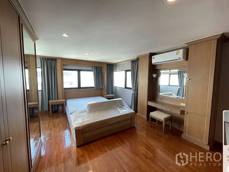 Condominium for rent - Master bedroom with dressing table under air conditioner and matching wood cabinetry.