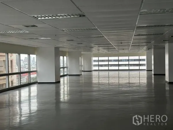 办公空间 出租 - 大型开放式办公室楼层，双面大窗、格栅吊顶照明，城市景观，位于曼谷瓦他那区。