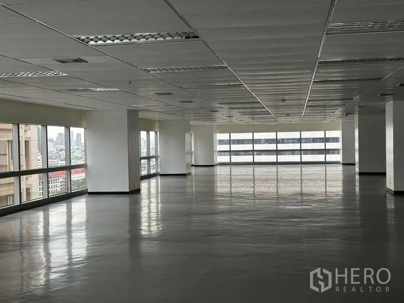 办公空间 出租 - 大型开放式办公室楼层，双面大窗、格栅吊顶照明，城市景观，位于曼谷瓦他那区。