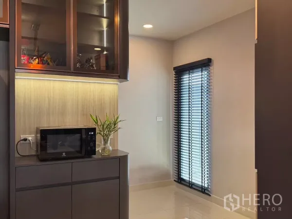 独立式住宅 出租在Bang Phli, Samut Prakan - 茶水吧角落，微波炉、玻璃门吊柜与百叶窗。