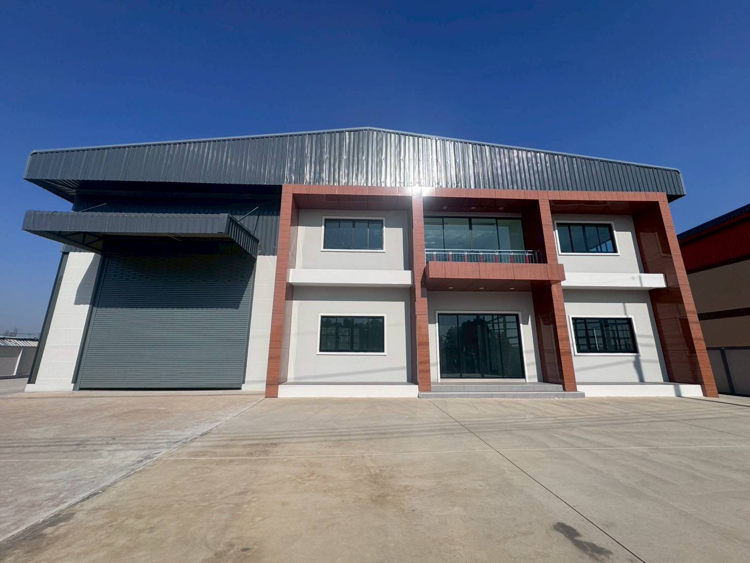 โรงงาน ขายในMueang Samut Sakhon, Samut Sakhon - ภายนอกโรงงานสมัยใหม่ ประตูม้วนขนาดใหญ่ สำนักงานสองชั้น และลานคอนกรีตกว้าง