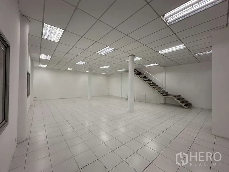 Factory for rent in Khlong Luang, Pathum Thani - Open-plan office area on the mezzanine with staircase and multiple windows.