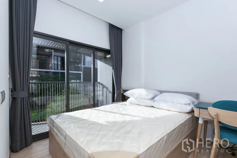 Condominium for rent in Watthana, Bangkok - Bedroom with large sliding glass door to balcony, double bed and study desk.