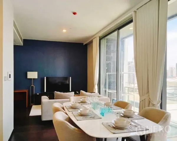 公寓 出租在Watthana, Bangkok - 靠落地窗的餐桌与起居区，阳台栏杆清晰可见。