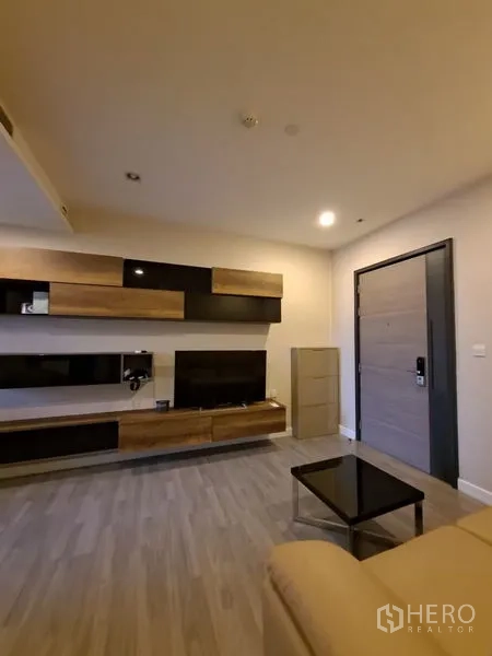 Condominium for rent in Bang Rak, Bangkok - Living area featuring built-in media wall, coffee table, and light wood flooring.