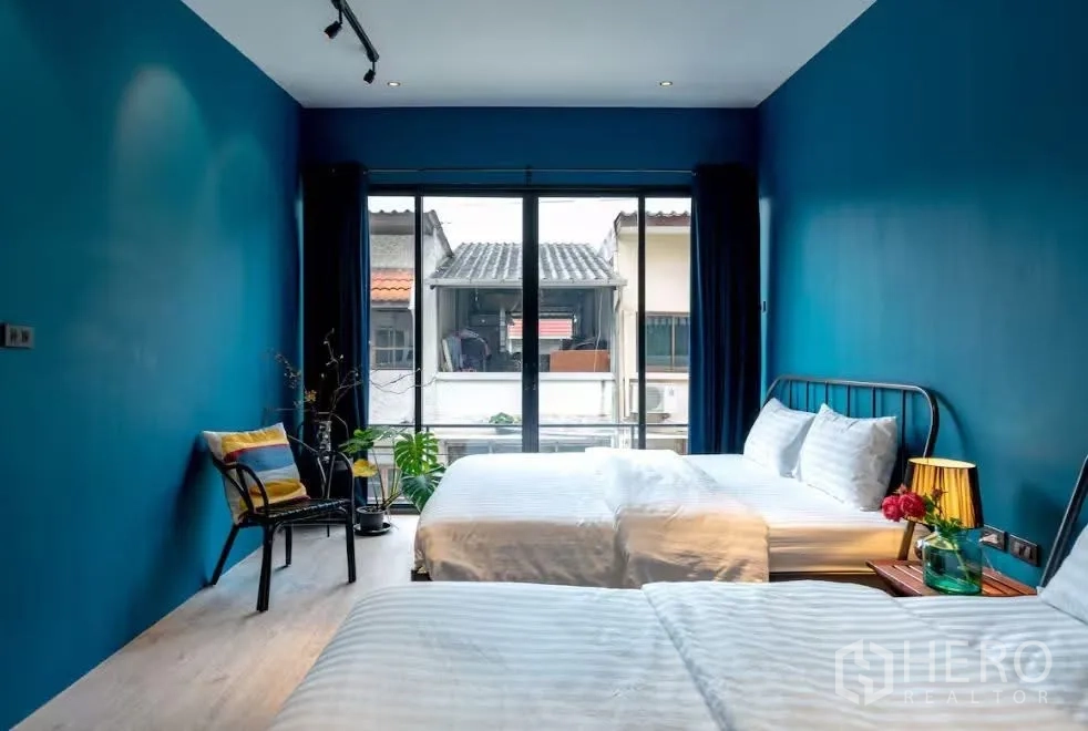 联排别墅 for rent in Watthana, Bangkok - 明亮卧室，双床配置，蓝色墙面，落地窗与阳台景观。