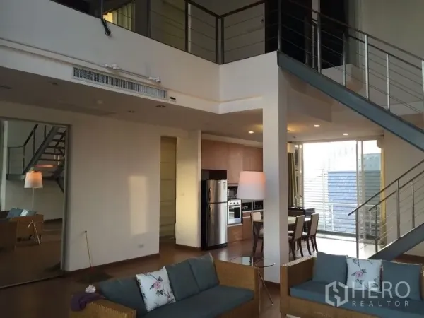 Condominium for rent in Chatuchak, Bangkok - Double-height living area with mezzanine, open kitchen and steel staircase in a duplex condo.