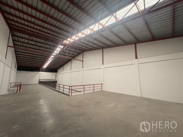Factory for rent in Phra Samut Chedi, Samut Prakan - Wide concrete mezzanine beneath an insulated metal roof with central skylight strip.