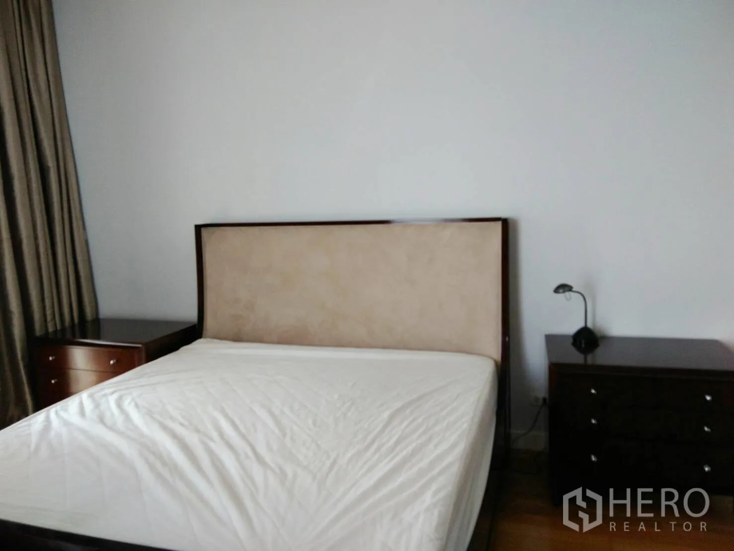 Condominium for rent in Khlong Toei, Bangkok - Bright bedroom with upholstered headboard, bedside tables, and floor-to-ceiling curtains.