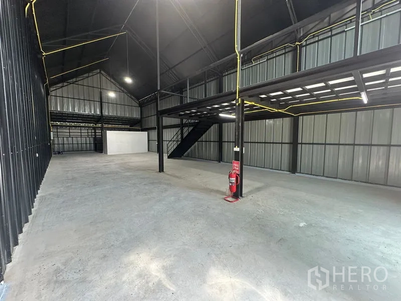 Warehouse for rent in Bueng Kum, Bangkok - Spacious high-ceiling warehouse interior with steel columns, mezzanine platform, and concrete floor.