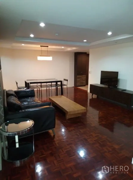 Condominium for rent in Watthana, Bangkok - Spacious living and dining area with parquet floors, leather sofa, TV console, and modern pendant lighting in an Ekkamai condo.