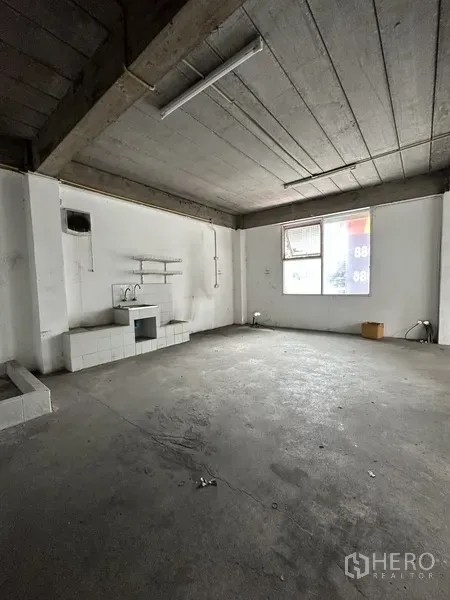 Retail Space for rent in Khlong Toei, Bangkok - Raw concrete retail area featuring a sink, wall shelving, exposed ceiling and a window.