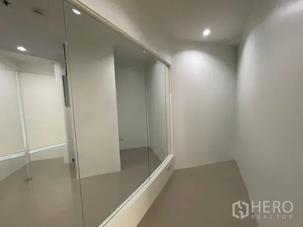 Office Space for rent in Khlong Toei, Bangkok - Narrow corridor with a large internal glass partition and recessed spotlights in a white office.