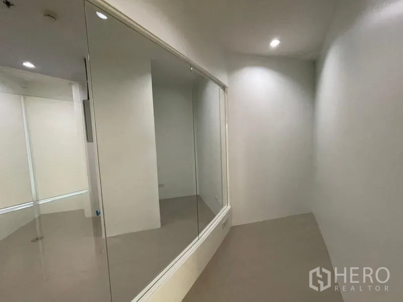 Office Space for rent in Khlong Toei, Bangkok - Narrow corridor with a large internal glass partition and recessed spotlights in a white office.
