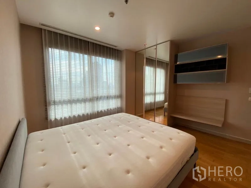 Condominium for rent or sale in Yan Nawa, Bangkok - Primary bedroom with large windows, mirrored wardrobe, wall shelving and mattress on bed frame.