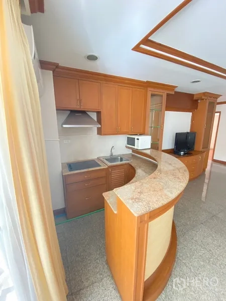 房间 出租在Watthana, Bangkok - 紧凑厨房，木质橱柜、灶台、抽油烟机与弧形石面台。