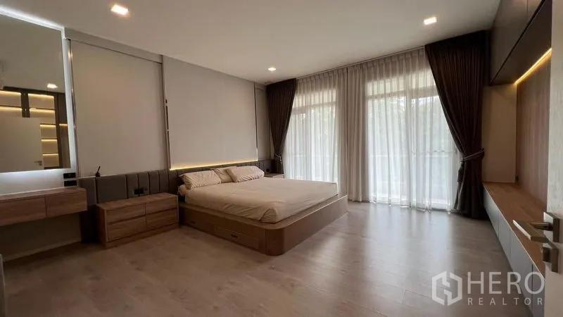 Detached House for rent in Prawet, Bangkok - Wide view of the master suite with wood floors, balcony doors and soft ambient lighting.