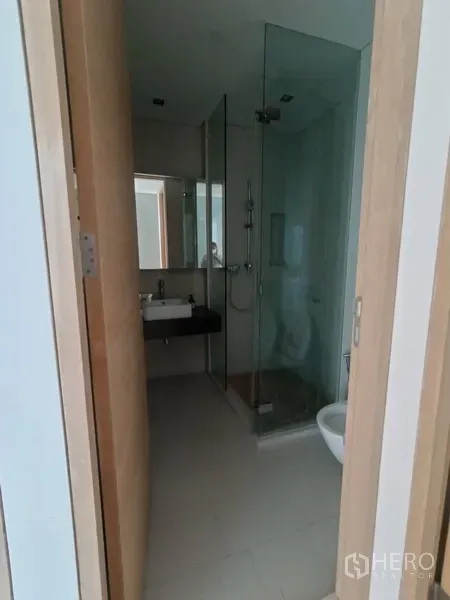 Condominium for rent or sale in Bang Rak, Bangkok - Second bathroom with glass shower, toilet and compact vanity.