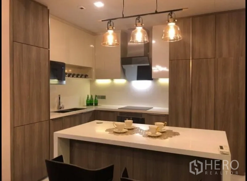 公寓 出租在Watthana, Bangkok - 全配套厨房，木纹柜体、白色台面与中岛吧台。