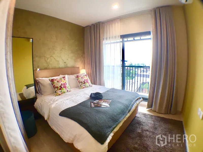 Condominium for rent in Khlong Toei, Bangkok - Second bedroom opening to a balcony through sliding glass door with curtains and area rug.