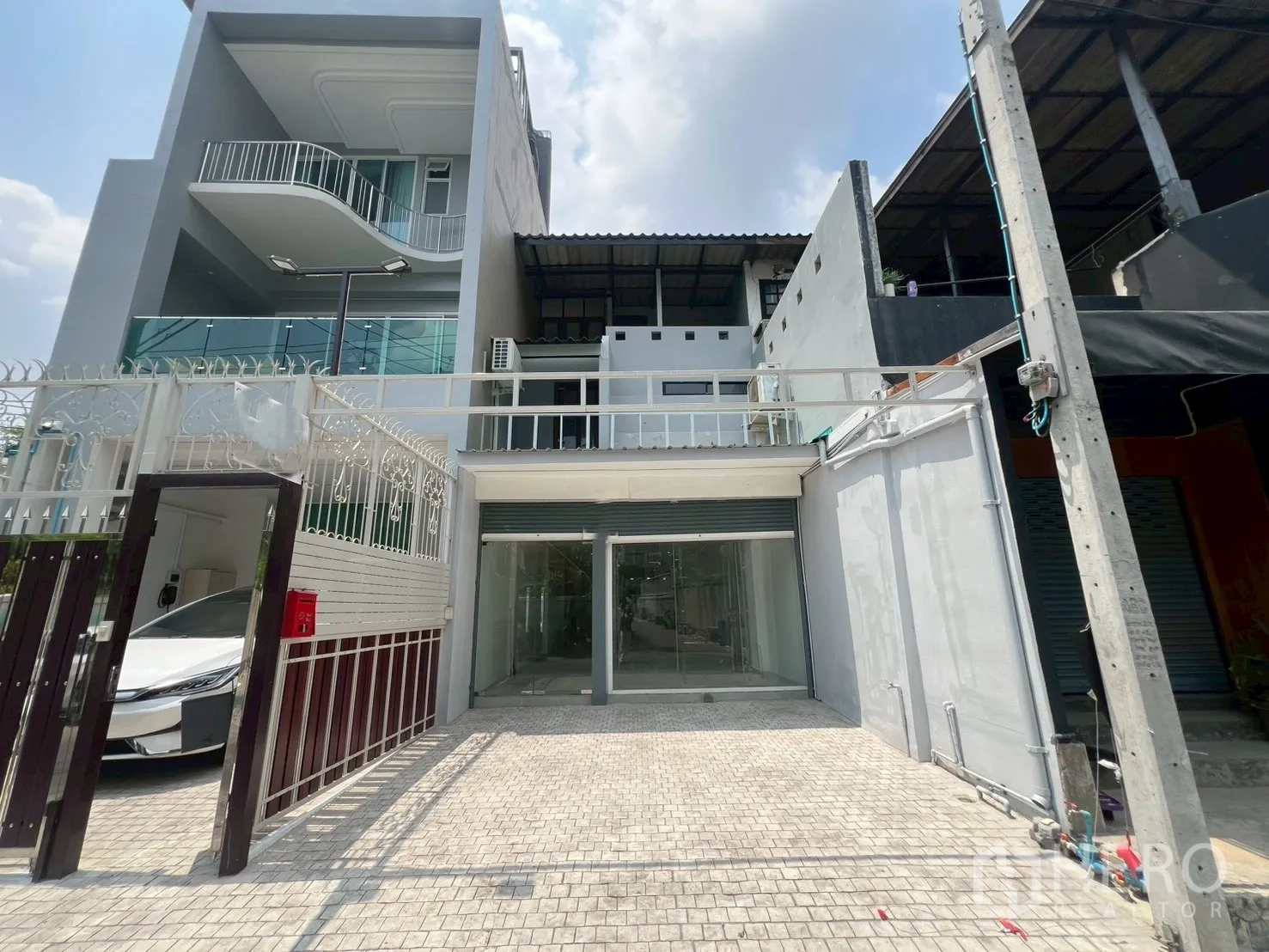 Home Office for rent in Watthana, Bangkok - Modern multi-storey home office exterior with gated driveway, glass balconies, and a roller shutter entrance.