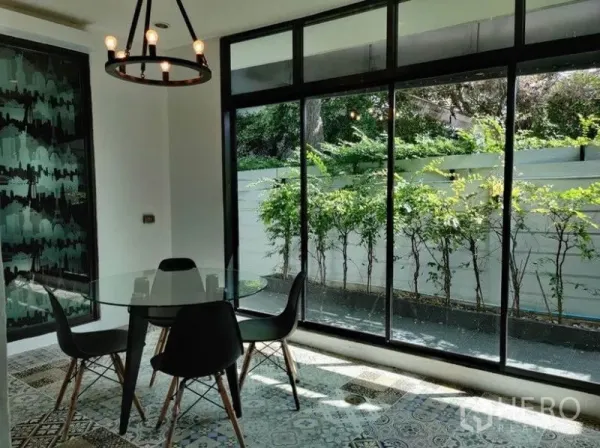 Townhouse for rent in Suan Luang, Bangkok - Bright dining area with glass walls opening to a small landscaped garden.