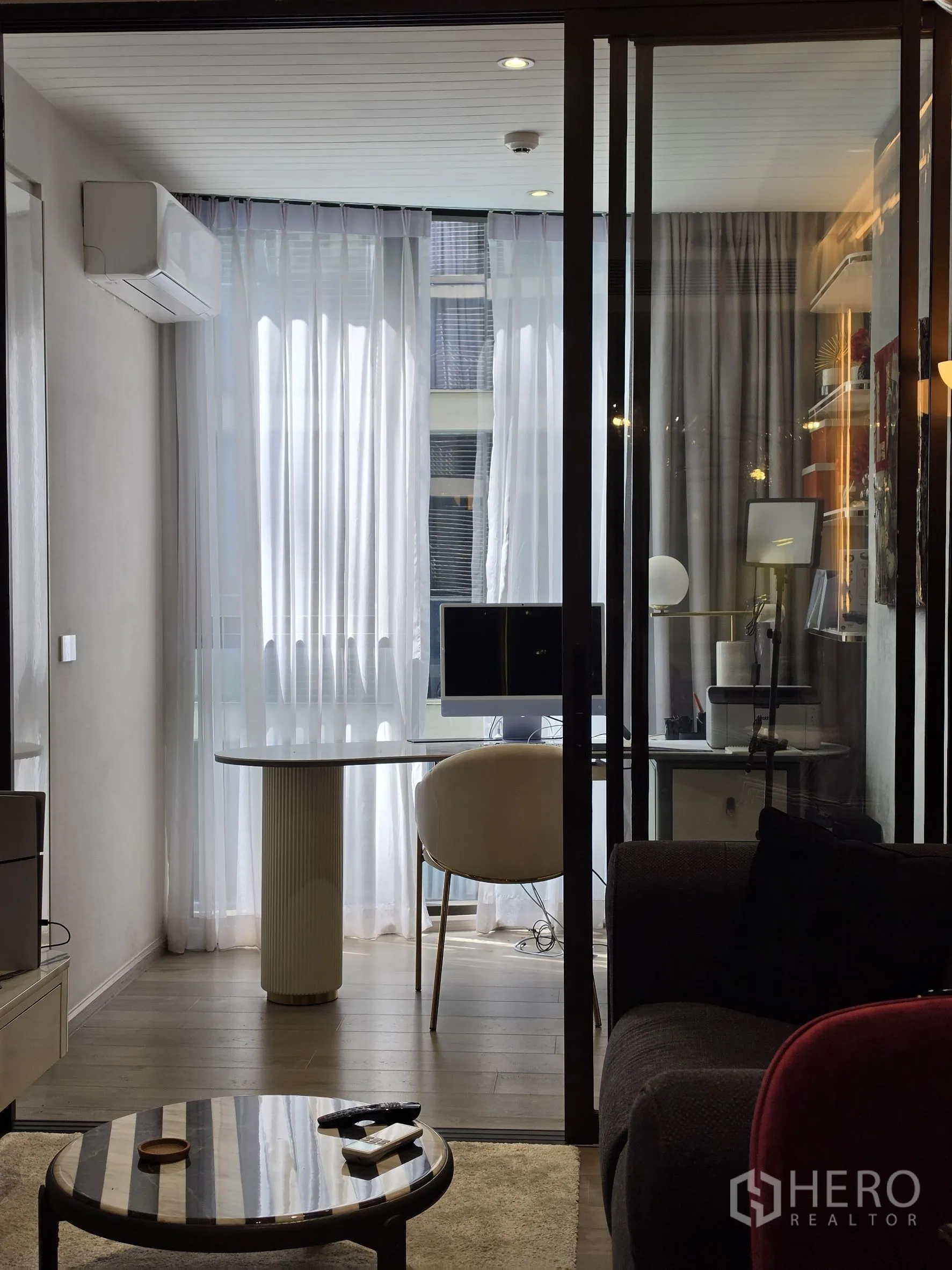 Condominium for rent in Khlong Toei, Bangkok - Sunlit study area behind sliding glass with sheer curtains.