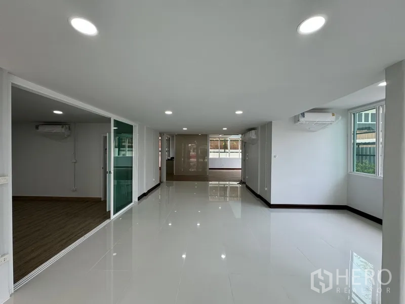Townhouse for sale in Bueng Kum, Bangkok - Open-plan living or office space with glossy white tiles and recessed lighting.