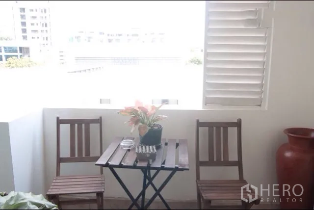 公寓 出租或出售在Watthana, Bangkok - 舒适阳台，小圆桌与两把椅子，可观城市景致。