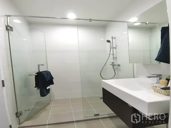 公寓 出租或出售在Watthana, Bangkok - 明亮卫生间，玻璃干湿分离步入式淋浴与宽大台盆。