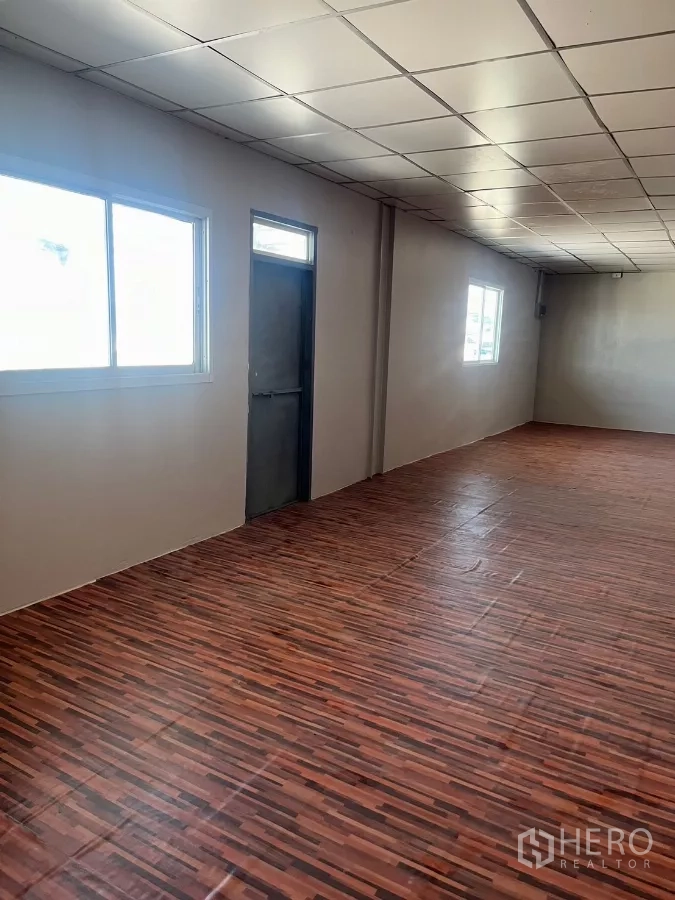 Warehouse for rent in Lat Lum Kaeo, Pathum Thani - Bright office area with wood-style flooring, windows, and a metal door.