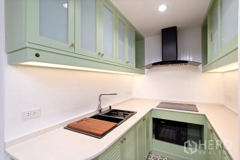 公寓 for rent in Watthana, Bangkok - L形厨房配薄荷绿橱柜、灶台与抽油烟机。
