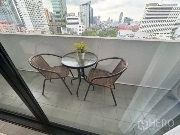 Condominium for rent in Watthana, Bangkok - Private balcony with round table and two rattan chairs overlooking the Bangkok skyline.