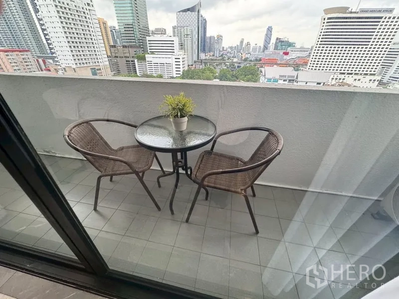Condominium for rent in Watthana, Bangkok - Private balcony with round table and two rattan chairs overlooking the Bangkok skyline.