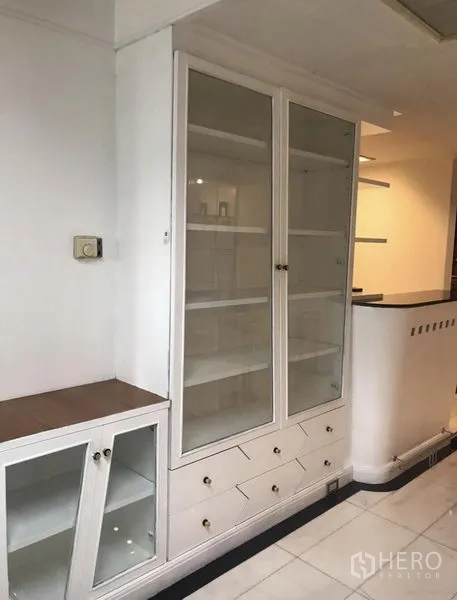 Condominium for rent in Khlong Toei, Bangkok - White built-in cabinet with glass doors and drawers providing ample storage near the kitchen.