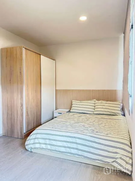 Townhouse for rent in Bang Phli, Samut Prakan - Second bedroom with striped bedding, wardrobe and soft lighting.
