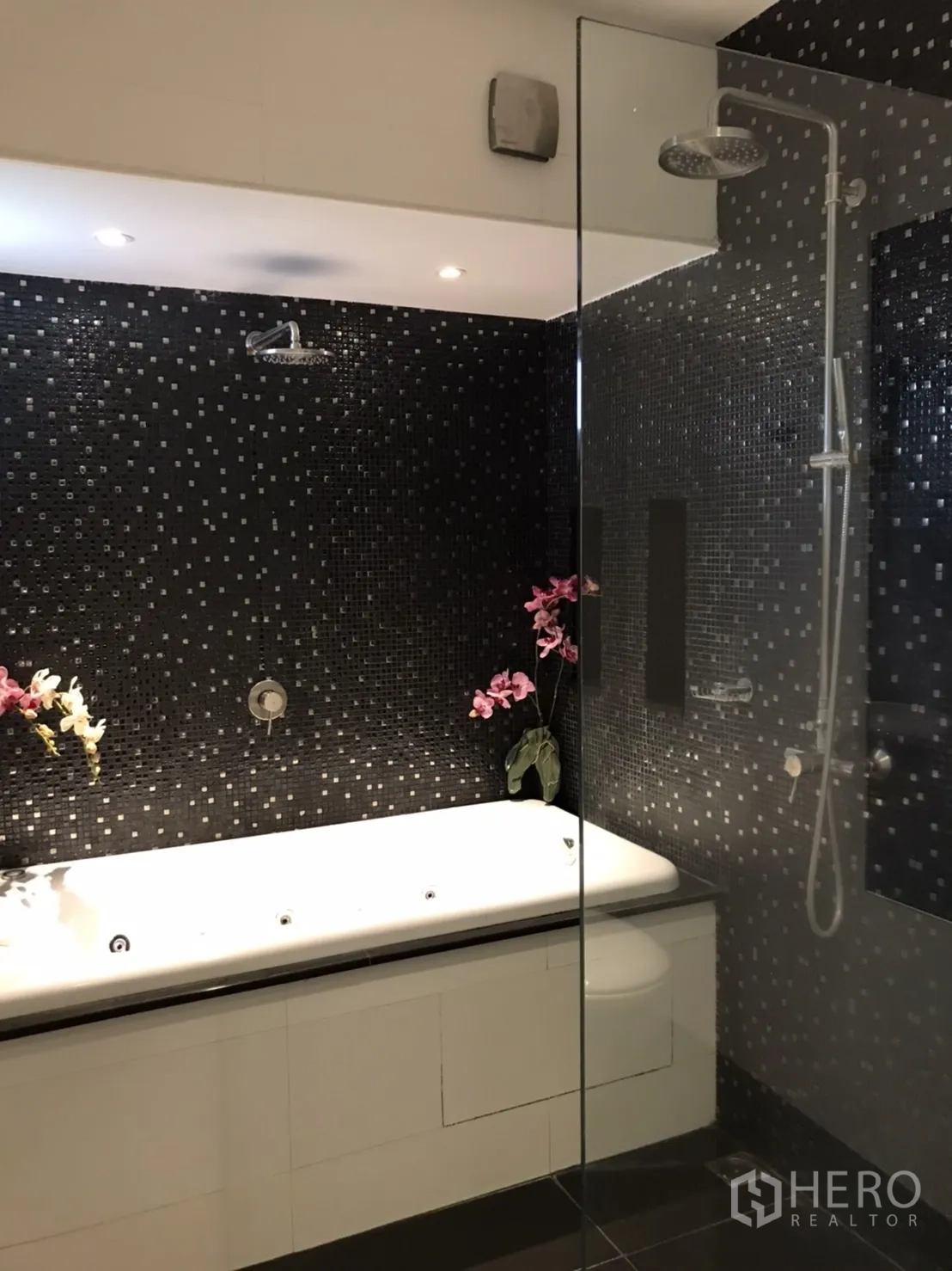 Detached House for rent or sale in Saphan Sung, Bangkok - Ensuite bathroom with black mosaic feature wall, glass shower and white bathtub.