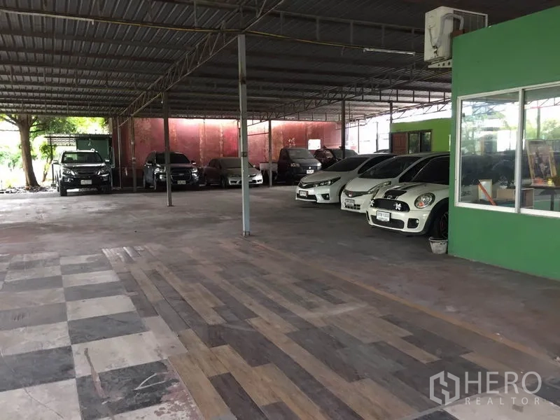 Warehouse for rent in Pathum Thani - Row of cars parked inside a covered warehouse next to an onsite office room.