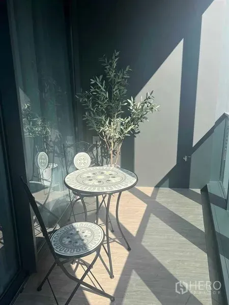 Condominium for rent in Khlong Toei, Bangkok - Private balcony with bistro table and chairs, glass railing, and potted plant.