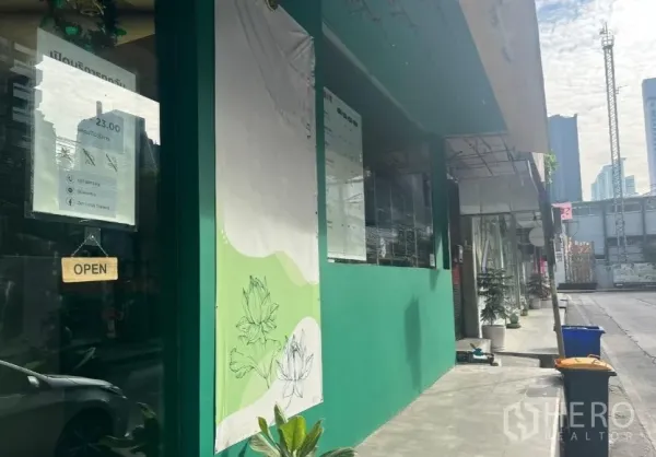 Retail Space for rent in Khlong Toei, Bangkok - Angled view of the storefront on a busy street with glass windows and city high‑rises ahead.