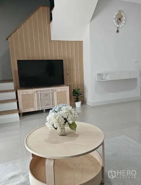 Townhouse for rent in Bang Phli, Samut Prakan - Modern lounge with TV unit by the stairs, tiled floors and a light wooden coffee table.